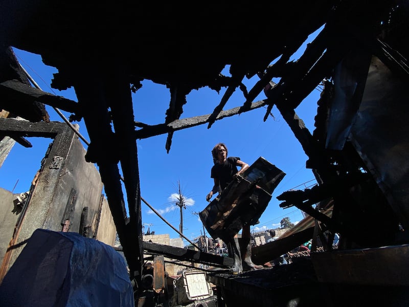 A resident retrieves belongings following a fire in a residential district of Las Pinas city, Metro Manila, Philippines. EPA