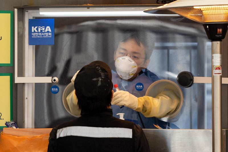 A healthcare worker standing inside a container collects a sample from a visitor at a temporary Covid-19 testing station outside Seoul City Hall in Seoul. Bloomberg