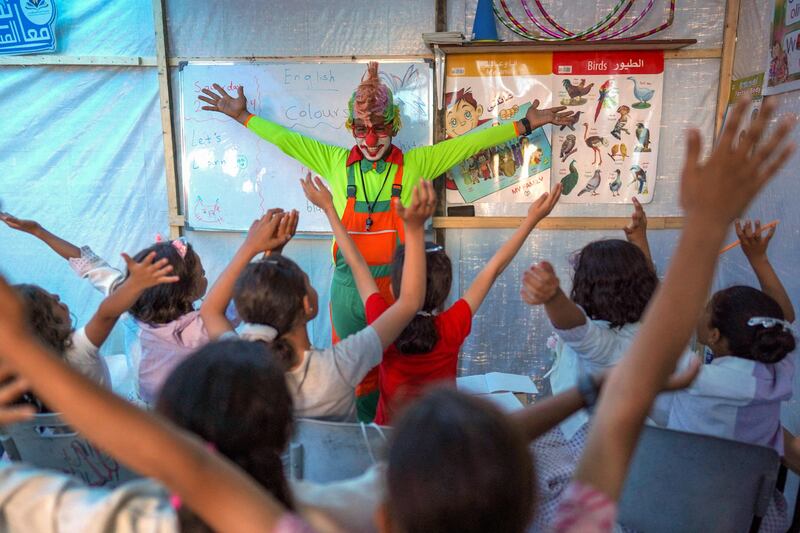 A man dressed as a clown entertains children at a makeshift school in a camp for displaced Palestinians in Deir El Balah, the central Gaza Strip. AFP