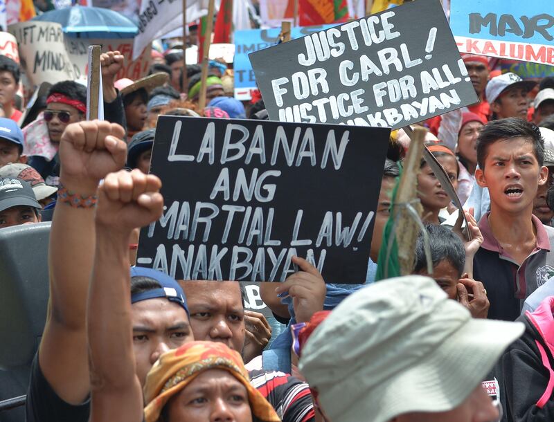 Protesters raise clenched fists next to an anti-martial law placard during a rally near the US embassy in Manila on September 15, 2017.
Philippine President Rodrigo Duterte may declare nationwide martial law next week if threatened massive protests by communists and other leftists against his rule turn violent or disrupt the country, his defence chief said on September 15. / AFP PHOTO / TED ALJIBE