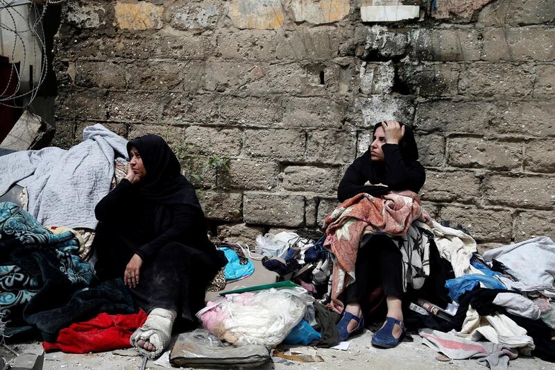 Palestinians sit with their belongings in a street outside their destroyed house. Reuters