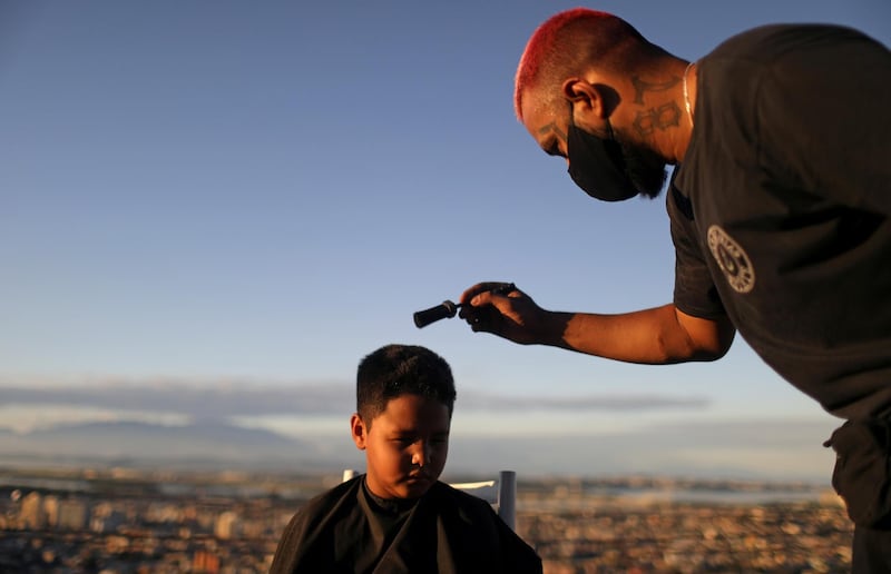 Barber Renan Estate gives a haircut to a child at home as part of his "Delivery Barber" service, as his shop is closed due to the coronavirus disease (COVID-19) outbreak, in the Complexo do Alemao slum in Rio de Janeiro, Brazil. REUTERS