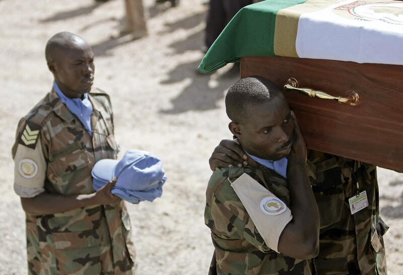 In a photograph made available by Albany Associates on July 12 2008, soldiers and civilian staff serving with the United Nations-African Union Mission in Darfur (UNAMID) pay their respects during a funeral ceremony for seven peacekeepers who were killed in an ambush by armed gunmen while returning from patrol in the Northern Darfur State on July 08. The deaths of the five Rwandan protection force peacekeepers and two police officers from Ghana and Uganda was the greatest loss of lives the mission has suffered since it took over from its African Union predecessor on 1 January this year. Twenty two others were wounded in the attack. STUART PRICE / ALBANY ASSOCIATES -RESTRICTED TO EDITORIAL USE- (Photo by STUART PRICE / ALBANY ASSOCIATES / AFP)
