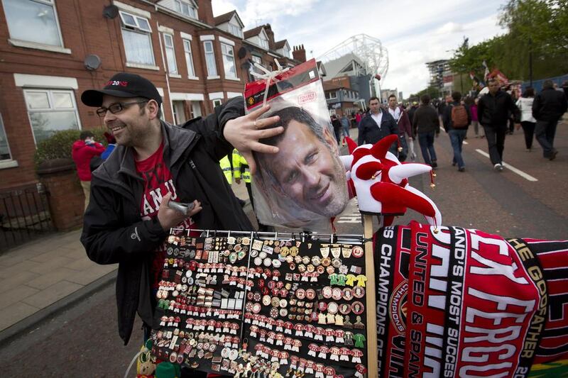 A merchandise seller stands alongside his stall featuring a mask of Giggs before the game. There was a sense of excitement after the Welshman was hired on an interim basis. Jon Super / AP Photo