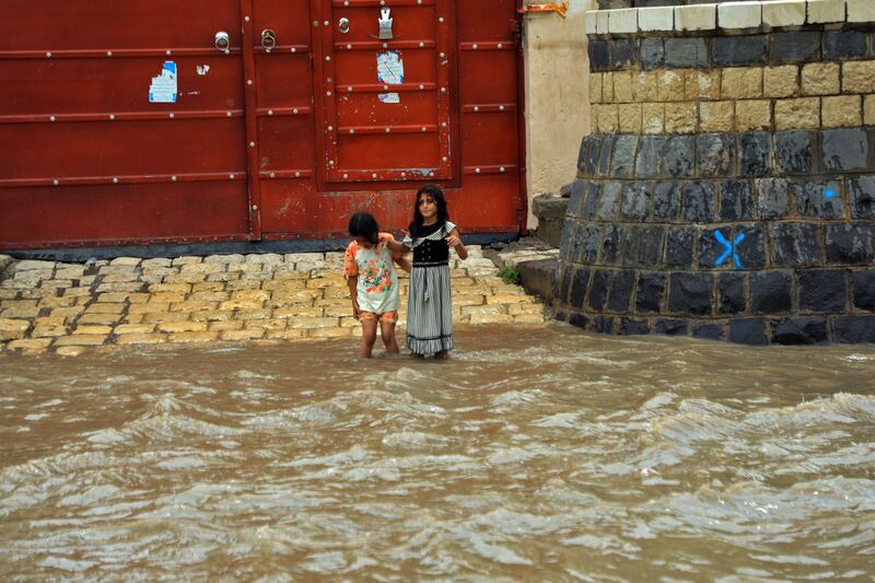 Girls cross a flooded street in the old city of Sanaa. AFP