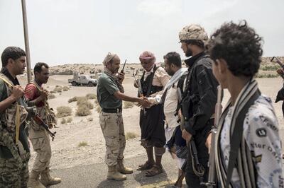 An army officer of the Tarik Salih' brigade (3rdL) shakes hands with Ahmed Al- Kawkabani, the leader of Tuhama Brigade,  3rd R , close to a front line in al-Hudayda outskirts as they discuss the advance of their joined troops fighting the Houthis, along the west coast. May 15, 2018.  Photo/ Asmaa Waguih 