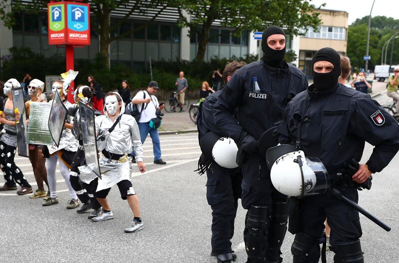 German riot police officers stand next to protesters during demonstrations against the G20 summit in Hamburg on July 8, 2017. Pawel Kopczynski / Reuters