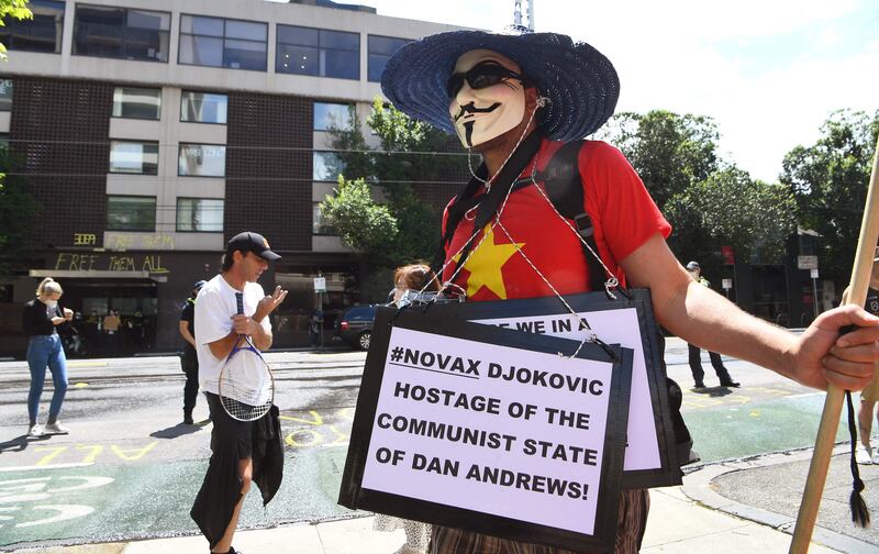 An anti-vax protester holds placards at a government detention centre where Serbia's tennis champion Novak Djokovic is reported to be staying. AFP