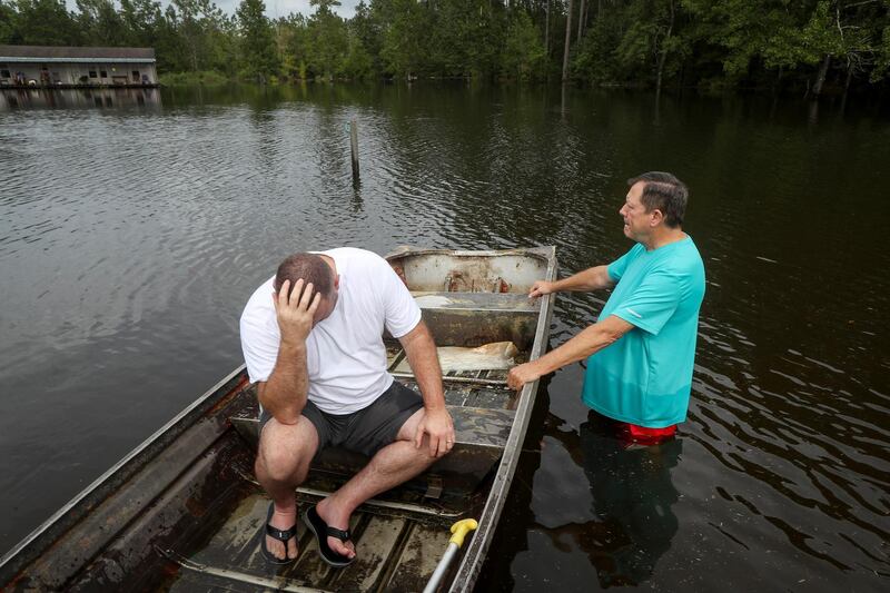 Stephen Gilbert, left, and his father-in-law sit in front of their flooded property on Friday, Sept. 20, 2019, in the Mauriceville, Texas, area. Floodwaters are starting to recede in most of the Houston area after the remnants of Tropical Storm Imelda flooded parts of Texas. "I'm on my third house," said Gilbert, who lives behind his father-in-law. "I wouldn't go anywhere else in the world," he said. "All we have is family anyway." ( Jon Shapley/Houston Chronicle via AP)