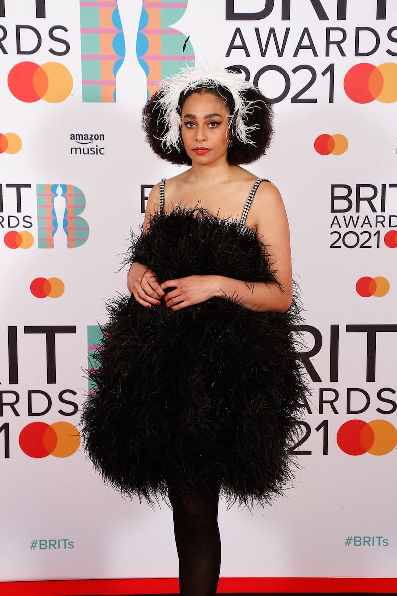 Celeste poses on the red carpet in a black feathered gown with a matching feathered headband for the Brit Awards. Reuters