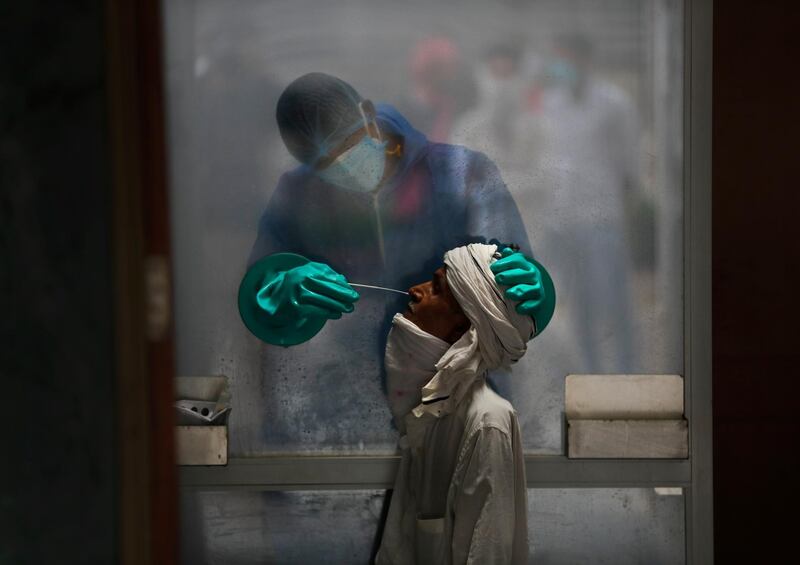 A health worker takes a nasal swab of a person for a Covid-19 test at a hospital in New Delhi, India. AP Photo