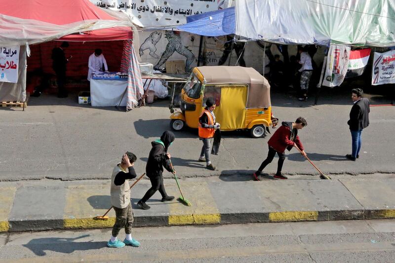 Iraqi protesters clean a street at Baghdad's Tahrir square on February 23, 2020.  AFP