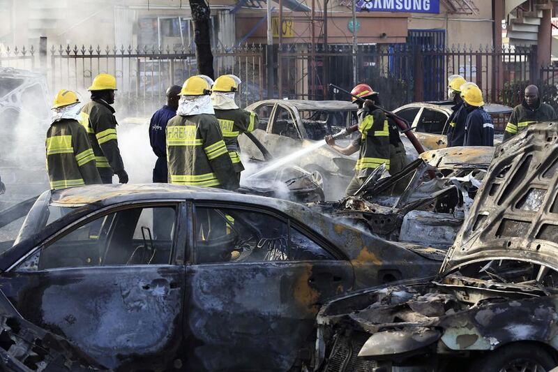 Firefighters douse cars after a bomb blast at a crowded shopping district in the Nigerian capital, Abuja, on June 25, 2014, that killed at least 21 people. Afolabi Sotunde / Reuters