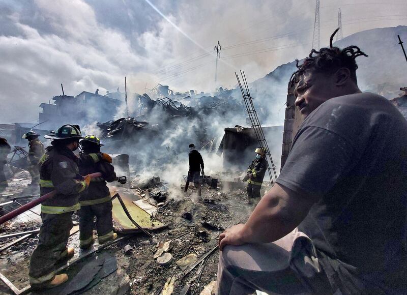 Firefighters battle a blaze that affected dozens of temporary  homes at two migrants camps in Antofagasta, Chile. AFP