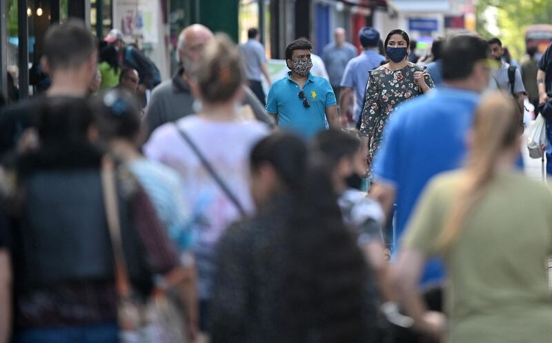 Pedestrians, some wearing masks, walk past shops in Hounslow, west London. AFP