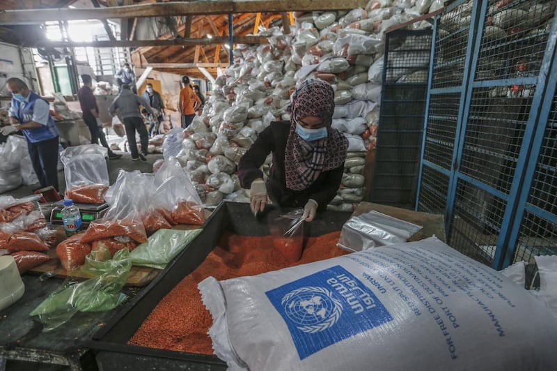 Palestinian employees at the United Nations Relief and Works Agency for Palestinian Refugees (UNRWA) wearing protective masks and gloves, prepare food aid rations to be henceforth delivered to refugee family homes rather than distributed at a UN a center, in Gaza City, on March 31, 2020, due to the COVID-19 pandemic. (Photo by MAHMUD HAMS / AFP)