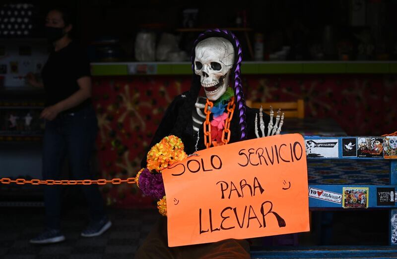 A skeleton dummy with a sign reading "Takeaway Food Only" sits at the entrance of a restaurant in Mexico City.   AFP