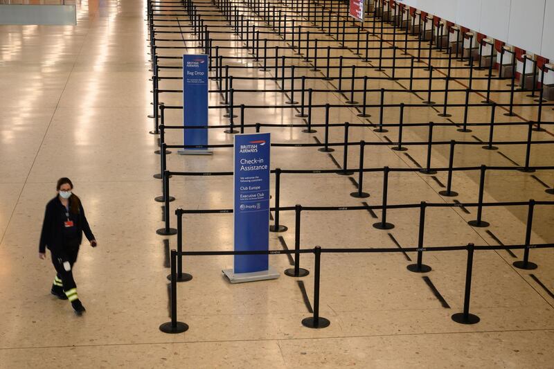 A medical staff member wearing a protective mask walks past the empty British Airways' check-in area of Geneva Airport.  AFP