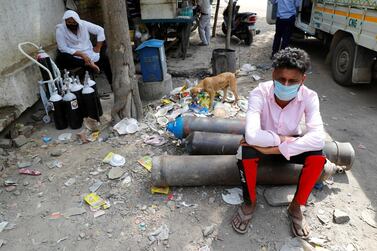 A man sits on an oxygen cylinder as he waits outside a factory in India's capital New Delhi to get it refilled, amid a shortage created by soaring numbers of Covid-19 cases. Reuters