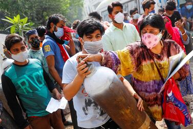 A woman and her son carry an oxygen cylinder outside a factory to get it refilled, amidst the spread of the coronavirus disease (COVID-19) in New Delhi, India, April 28, 2021. REUTERS/Adnan Abidi