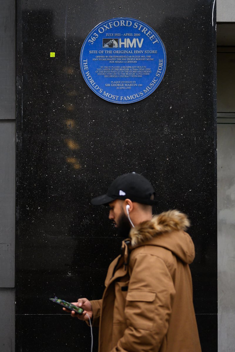 A blue heritage plaque is seen on the exterior of the building as a man passes the original branch of the HMV chain of music retailers in London, England. Getty Images