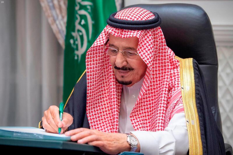 In this photo released by Saudi Press Agency, SPA, Saudi King Salman signs the 2021 state budget following a virtual cabinet meeting in Riyadh, Saudi Arabia, late Tuesday, Dec. 15, 2020. (Saudi Press Agency via AP)