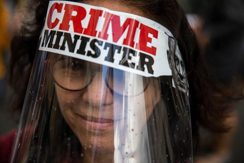 A protester against Israel's Prime Minister Benjamin Netanyahu wears a face mask during a protest outside his residence in Jerusalem.  AP Photo