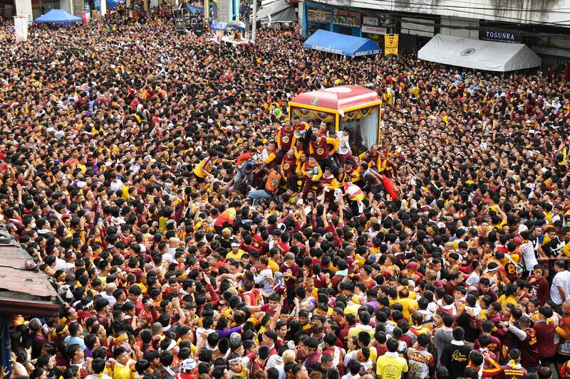 Catholic devotees jostle as they try to touch a glass-covered carriage carrying the Black Nazarene, during an annual religious procession in Manila. AFP
