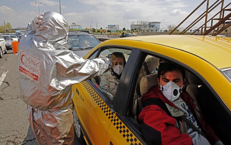 A member of Iranian Red Crescent tests people with possible coronavirus Covid-19 symptoms, as police blocked Tehran to Alborz highway. AFP