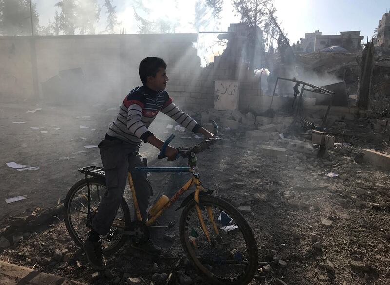 A Palestinian boy rides a bicycle near a militant target that was hit in an Israeli airstrike. Mohammed Salem / Reuters.