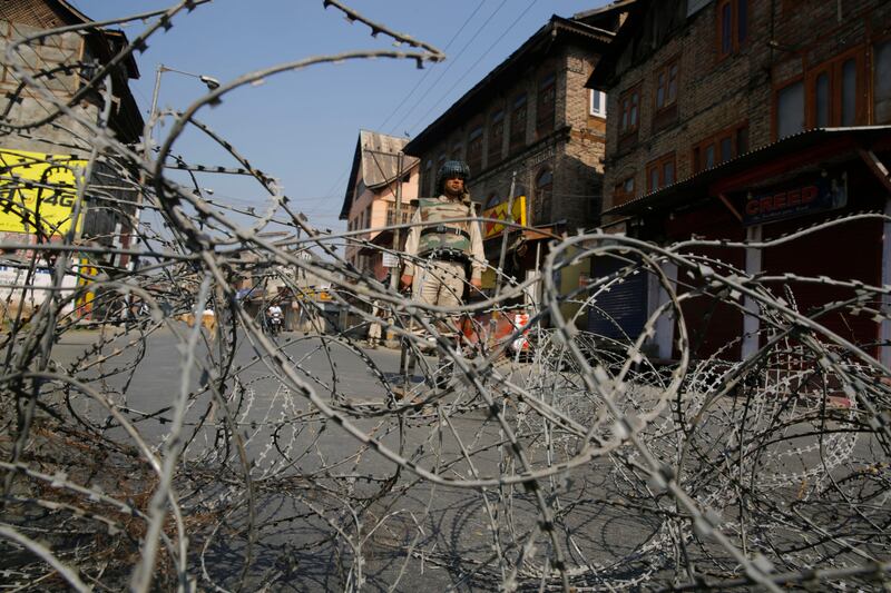 An Indian paramilitary soldier stands guard near barbed wire set as a temporary barricade during restrictions in downtown of Srinagar, the summer capital of Kashmir.  Farooq Khan / EPA