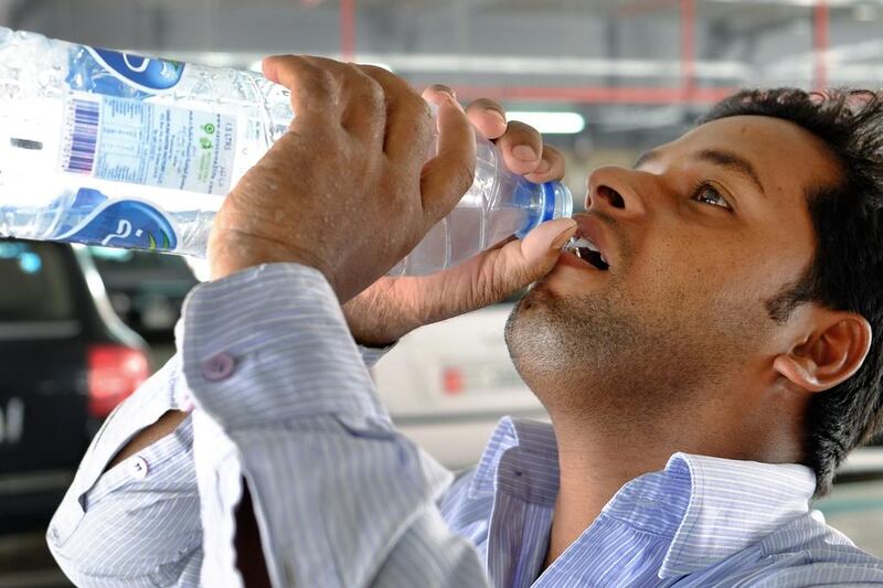 A worker drinks water to keep himself hydrated during a mandatory break for outdoor workers. The start of the mandatory break for outdoor workers across the UAE will last until September 15. Delores Johnson / The National  