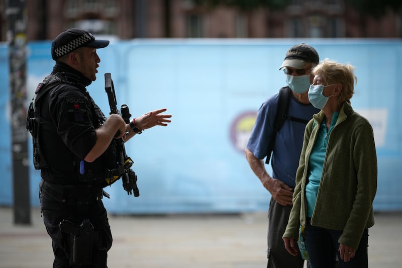 An armed police officer talks to members of the public wearing face masks in Manchester city centre. Getty Images
