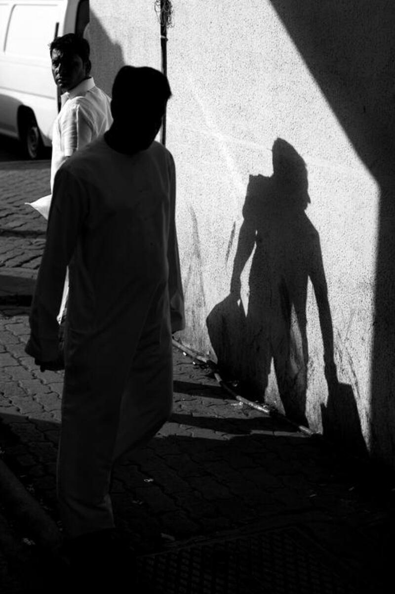 Men pass in an alley while running morning errands in downtown Abu Dhabi. Brian Kerrigan / The National