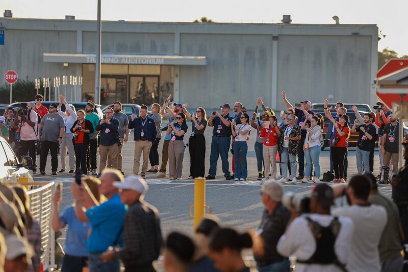 People cheer as the vehicle carrying the two Nasa astronauts  away from the operations and checkout building at Cape Canaveral. The countdown was stopped two hours before the planned lift-off. AFP