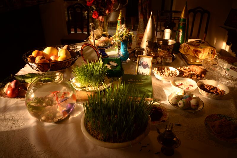 A table prepared for Nowruz. The items on the table represent concepts such as rebirth (wheat and barley), affluence (sweet pudding), love (olives), health (garlic), beauty (apples). Photo: Mobeen Ansari