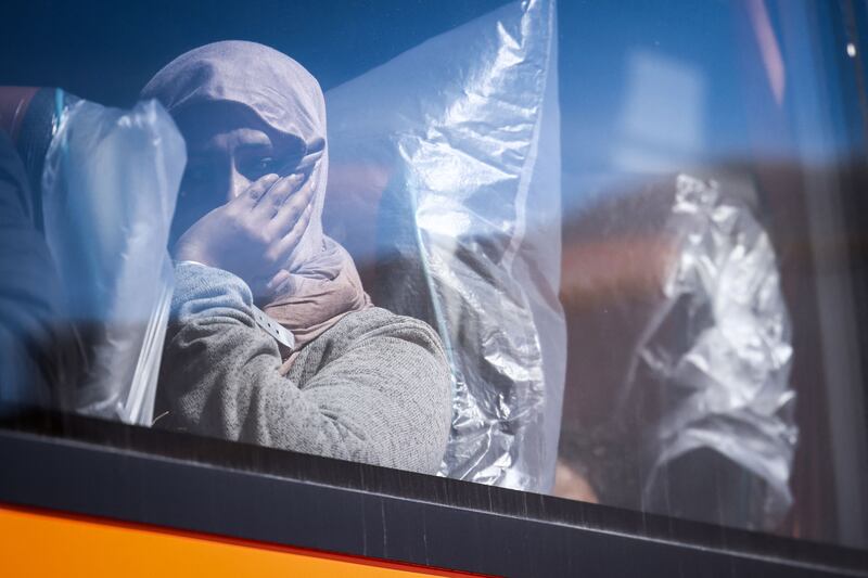 A woman looks out from the window of a bus taking her and other arrivals for processing. AFP