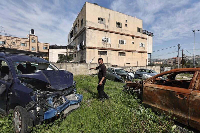 Palestinian mechanic and garage owner Motaz Qassrawi stands amid cars damaged during an attack by Israeli settlers in Huwara town in the occupied West Bank on March 13, 2024. AFP