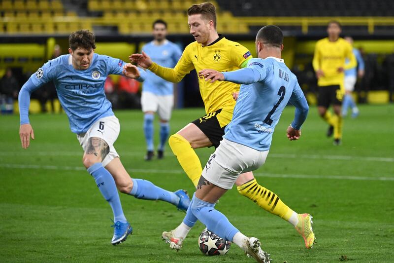 Dortmund's German forward Marco Reus (C) Manchester City's English defender John Stones (L) mand Manchester City's English defender Kyle Walker (R) vie for the ball during the UEFA Champions League quarter-final second leg football match between BVB Borussia Dortmund and Manchester City in Dortmund, western Germany, on April 14, 2021. (Photo by Ina Fassbender / various sources / AFP)