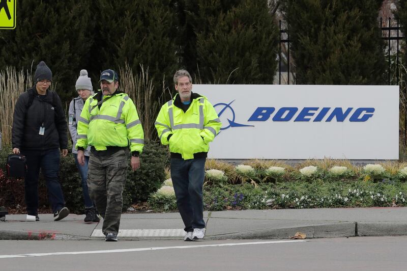 Workers walk past a Boeing Co. sign as they leave the factory where the company's 737 Max airplanes are built, Tuesday, Dec. 17, 2019, in Renton, Wash. As Boeing prepares to shutter much of the huge factory near Seattle that builds the grounded 737 Max jet, the economic hit is reverberating across the United States. The 737 Max, which analysts say is the largest manufactured product exported from the U.S., was grounded worldwide in March 2019 after the second of two deadly crashes in Indonesia and Ethiopia that killed a total of 346 people, and on Monday, Dec. 16, 2019, Boeing announced that it would halt Max production in January 2020 with no date for it to resume. (AP Photo/Ted S. Warren)