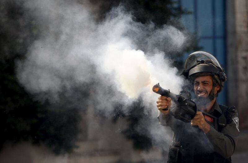 An Israeli policeman fires tear gas canisters during clashes with Palestinian protesters in the West Bank city of Hebron last week. Mussa Qawasma / Reuters