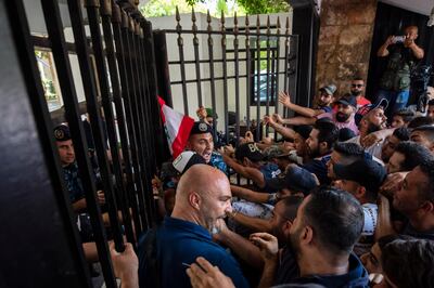 Anti-government protesters try to enter the main gate of the Lebanese interior ministry as they shout slogans against minister Mohammed Fahmi during a protest, in Beirut, Lebanon, Friday, July 3, 2020. (AP Photo/Hassan Ammar)