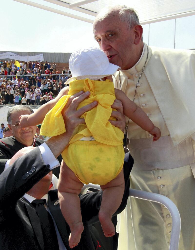 Pope Francis kisses a baby before celebrating a mass at the Amman stadium in the Jordanian capital on May 24, 2014. Pope Francis made an urgent plea today for peace in war-torn Syria as he kicked off a three-day pilgrimage to the Middle East. AFP PHOTO / KHALIL MAZRAAWI (Photo by KHALIL MAZRAAWI / AFP)