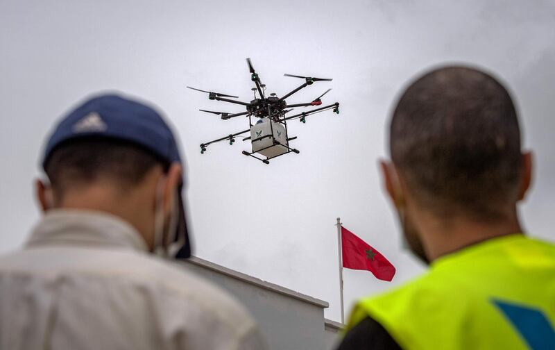 An employee of a Moroccan startup company pilots a drone equipped with disinfectant liquid, in a street of Harhoura near the capital Rabat on April 23, 2020, to be used during the novel coronavirus pandemic crisis. / AFP / FADEL SENNA
