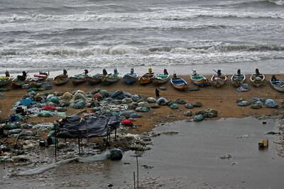 A man stands besides fishing nets next to boats stationed along a beach during heavy rainfall in Chennai. AFP