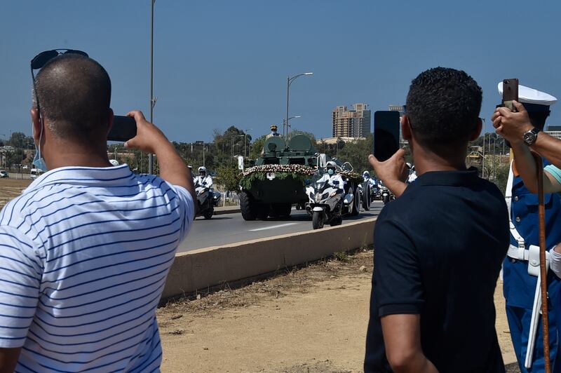 Algerian bystanders take pictures of the funerary motorcade of former president Abdelaziz Bouteflika as it advances to the El-Alia cemetery in the capital Algiers.  AFP