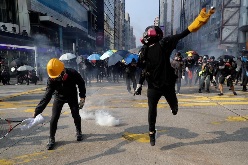 Protesters throw the tear gas canisters fired by riot policemen during a rally in Hong Kong. AP Photo