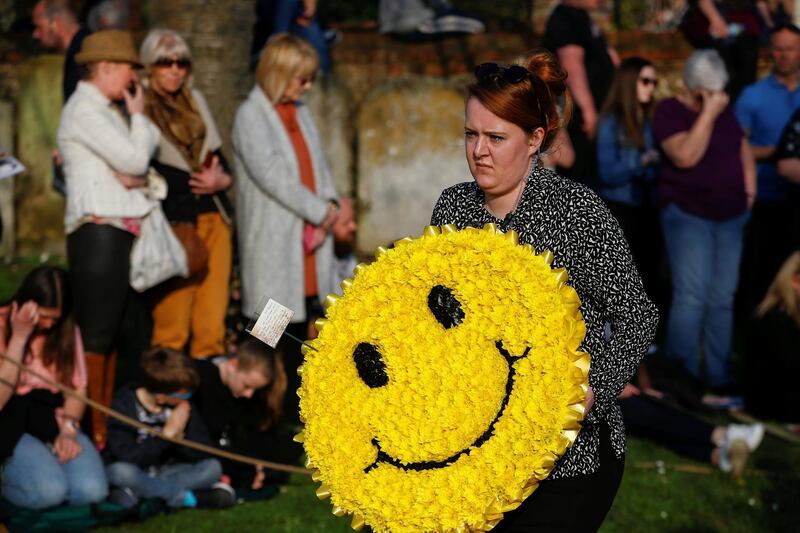 A floral wreath in shape of a smiley face is carried during the funeral. REUTERS