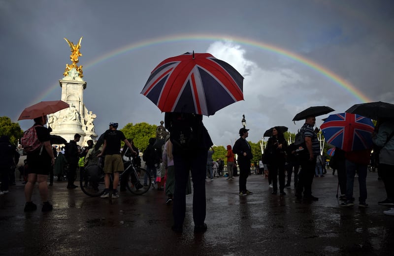 A man with a Union flag umbrella shelters from the rain near the Queen Victoria Memorial. AFP