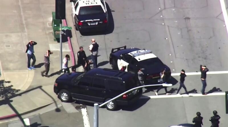 People walk away from the YouTube headquarters area after being searched by police. KGO-TV via AP